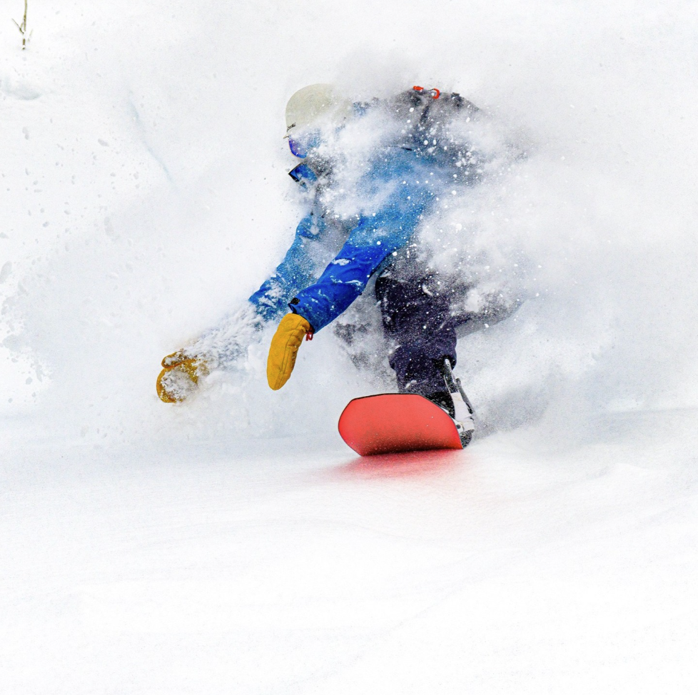Snowboarder som kjører gjennom puddersnø